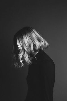 a black and white photo of a woman's back with her hair blowing in the wind