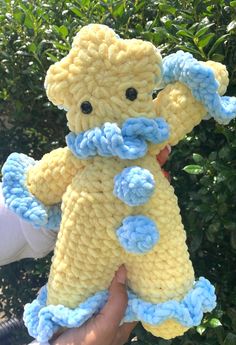 a hand holding a yellow and blue stuffed animal