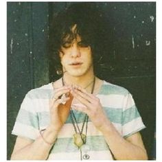 a young man standing in front of a black door with his hands on his chest