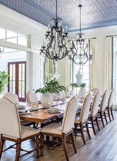 a dining room table with chairs and a chandelier hanging from it's ceiling