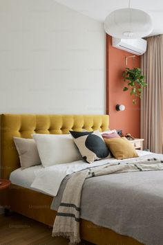 a bedroom with an orange accent wall and white bedding, along with a yellow headboard