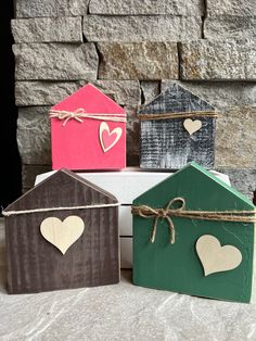 four small wooden houses with hearts tied to the front and sides, sitting next to each other