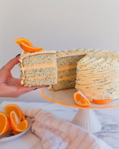 a person holding a slice of cake with oranges on the plate next to it