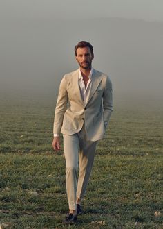 a man in a suit walking across a field