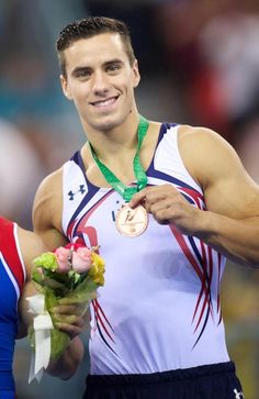 two men standing next to each other with medals on their necks and one holding flowers