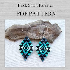 a pair of blue and black beaded earrings sitting on top of a piece of wood