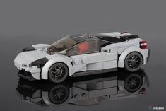 a lego car is shown on a reflective surface with its hood up and wheels down