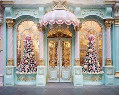 a pink and blue building with christmas decorations on the front door, decorated in pastel colors