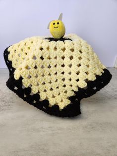 a crocheted blanket with a yellow smiley face on the top and black bottom