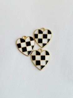 three black and white heart shaped buttons on a white surface, with one in the shape of a checkerboard pattern