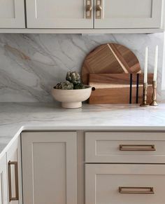 a white kitchen with marble counter tops and wooden cutting boards on the backsplash