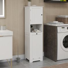 a washer sitting next to a tall cabinet in a room with beige walls and flooring