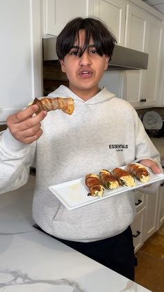 a person holding a plate with food on it and pointing to the camera while standing in a kitchen