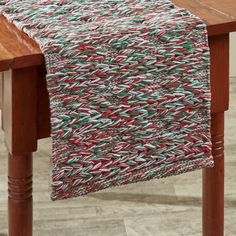 a red and green table runner on top of a wooden table next to a chair