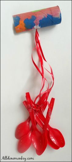 red balloons are tied to a corkscrew on a white surface with a paint roller in the background