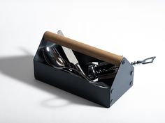 a black box with utensils in it on a white surface