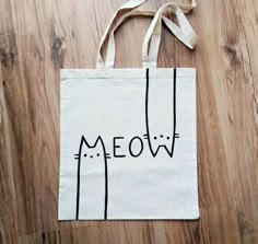 a white bag with the word meow written on it sitting on a wooden floor