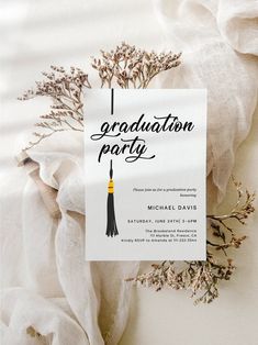 a graduation party card sitting on top of a white cloth with flowers in the background