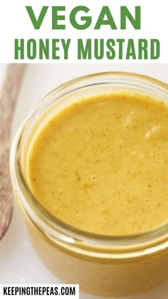 a jar filled with vegan honey mustard next to a spoon