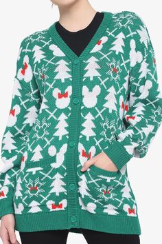 a woman wearing a green sweater with white and red christmas trees on the front,