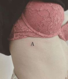 a woman's lower back tattoo with the letter a on her left ribcage