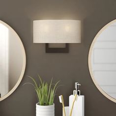 two round mirrors mounted on the wall above a sink with a toothbrush in it