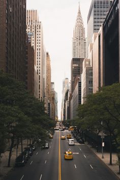 an empty city street with tall buildings in the background and taxi cabs on the road