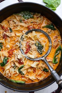 a skillet filled with pasta and spinach