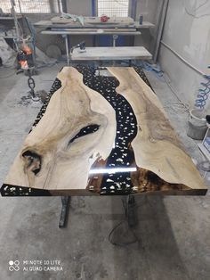 a table made out of wood with black and white designs on the top, sitting in a warehouse