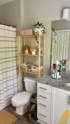 a white toilet sitting in a bathroom next to a sink and a shower curtain with flowers on it