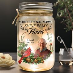 a lighted jar with an image of a cardinal on it and the words, your light will always shine in my heart