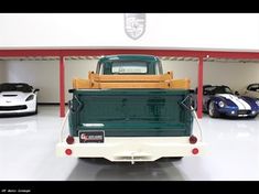 a green truck parked in a garage next to other cars