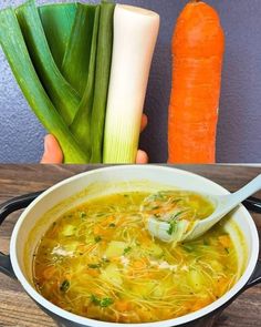 there is a bowl of soup with carrots and celery next to it