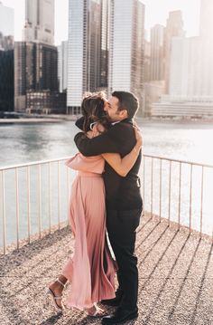 a man and woman kissing in front of the water