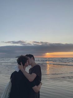 two people are kissing on the beach at sunset