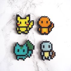 four pixelated pokemon pins sitting on top of a marble surface