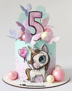 a birthday cake with a unicorn and balloons on the top is decorated in pastel colors