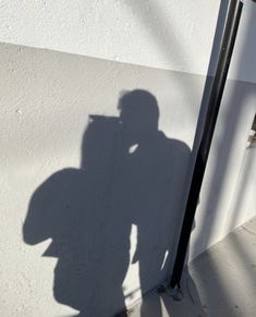 a shadow of a man on the side of a building with a cell phone in his hand