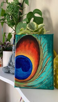 a painting of a peacock's tail on a shelf next to potted plants