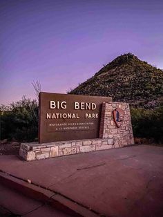 the big bend national park sign in front of a mountain at dusk with purple sky