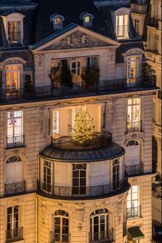 a tall building with a christmas tree on the top of it's balconies