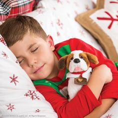 a young boy sleeping in bed with his stuffed dog