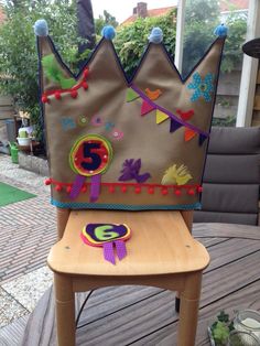 a brown chair with a crown on it's back sitting on a wooden deck