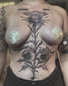 a woman with tattoos on her chest has flowers and leaves tattooed on her stomachs