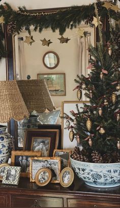 a decorated christmas tree sitting on top of a wooden table next to pictures and lamps