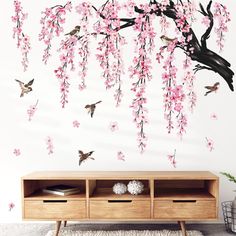 wall decals with pink flowers and birds flying over the branches in front of it