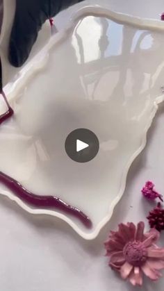 a white bowl with purple trim and flowers on the side, sitting on a table