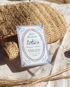 a wicker basket with a blue and white label sitting on top of it next to some straw