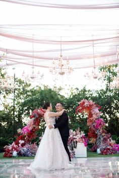 a bride and groom sharing a first dance at their wedding reception in front of flowers