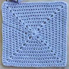 a blue crocheted square is shown on the floor